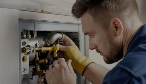 A Male Plumber Working on a Boiler